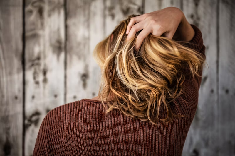 a hand running through a healthy head of hair