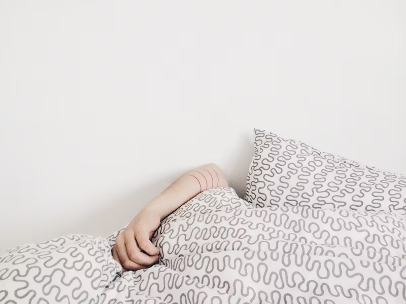 an arm sticking up out of bed covers