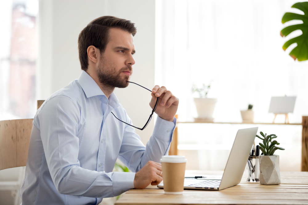 Thoughtful serious businessman lost in thoughts at work with laptop, focused executive thinking of problem solution, worried puzzled manager pondering question or solving business issues at workplace
