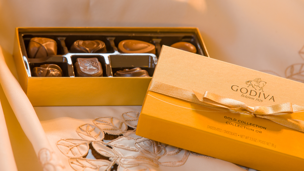 Boston, MA, USA 10/7/2020 — US version of the new Gold Collection by Godiva. Redesigned box from September 2020. 8 pieces package with the brand’s signature golden ribbon. Focus on the logo.