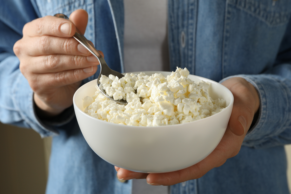 Woman hold bowl with cottage cheese, close up
