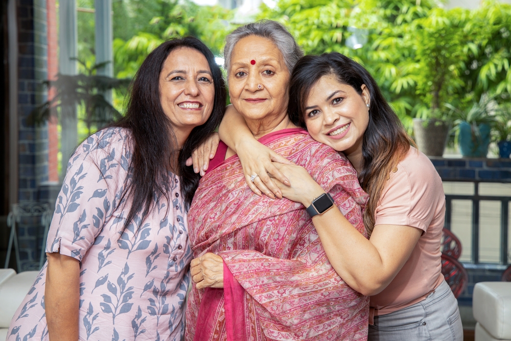 Two happy young indian daughters hug her mother at home, Love and bonding, Asian family.
