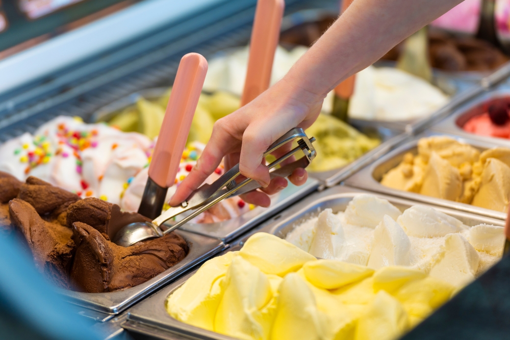 Ice cream showcase with a saleswoman preparing a chocolate flavored tub