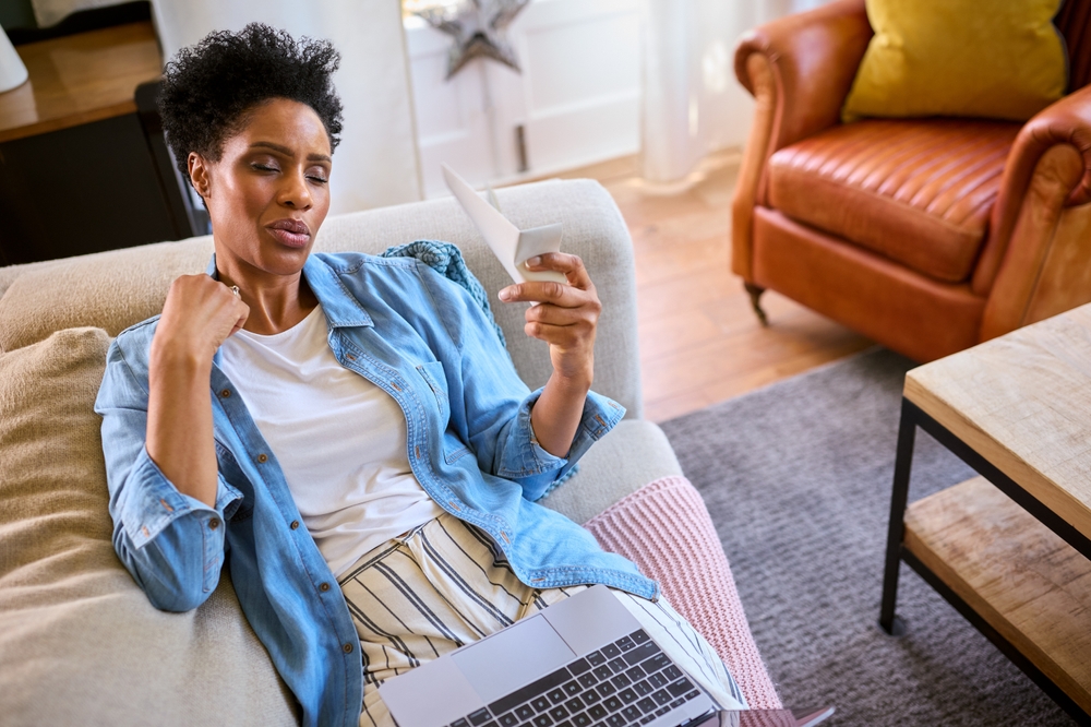 Menopausal Mature Woman At Home With Laptop Having Hot Flush Fanning Herself