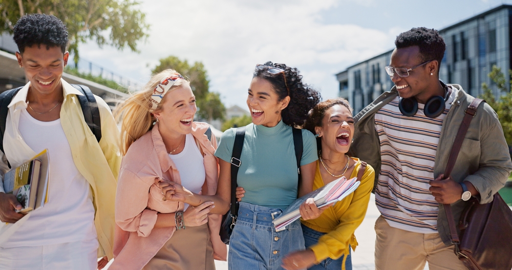 Walking, laughing and students at university with fun for learning, bonding and talking. People, diversity and group of gen z friends outdoor with books ready for education at college campus.