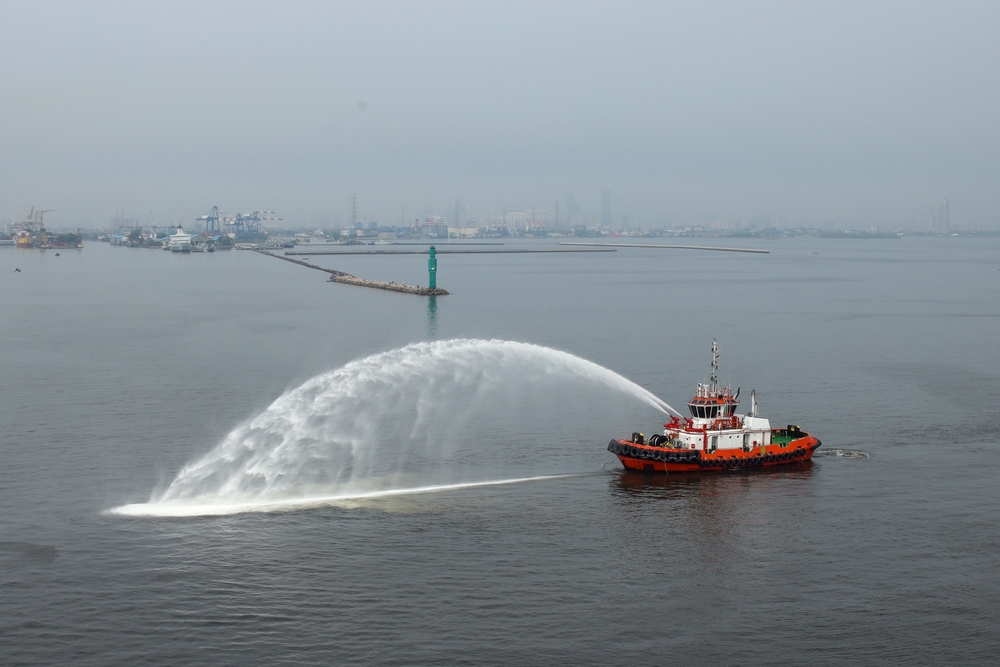 A Boat Spraying Water Perform Water Salute For Arrival Cruise Ship At The Dock
