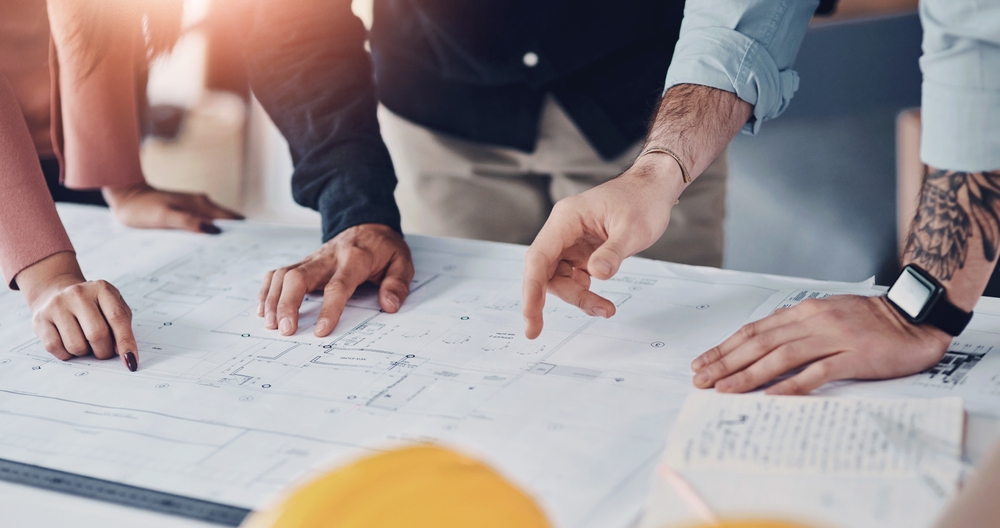 Hands, architect and blueprint sketch with clients for floor plan, drawing or renovation meeting of building construction. Group, contractor and document, planning and ideas of infrastructure project
