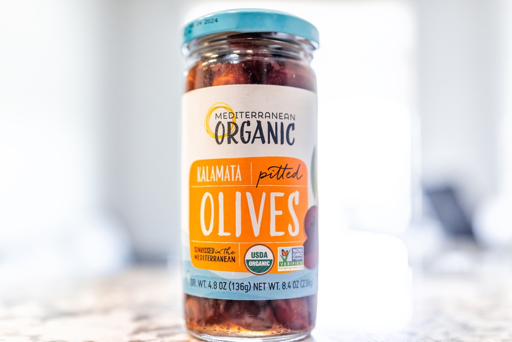 Avon, USA - June 27, 2022: Mediterranean organic kalamata pitted olives brand in brine macro closeup with bokeh background
