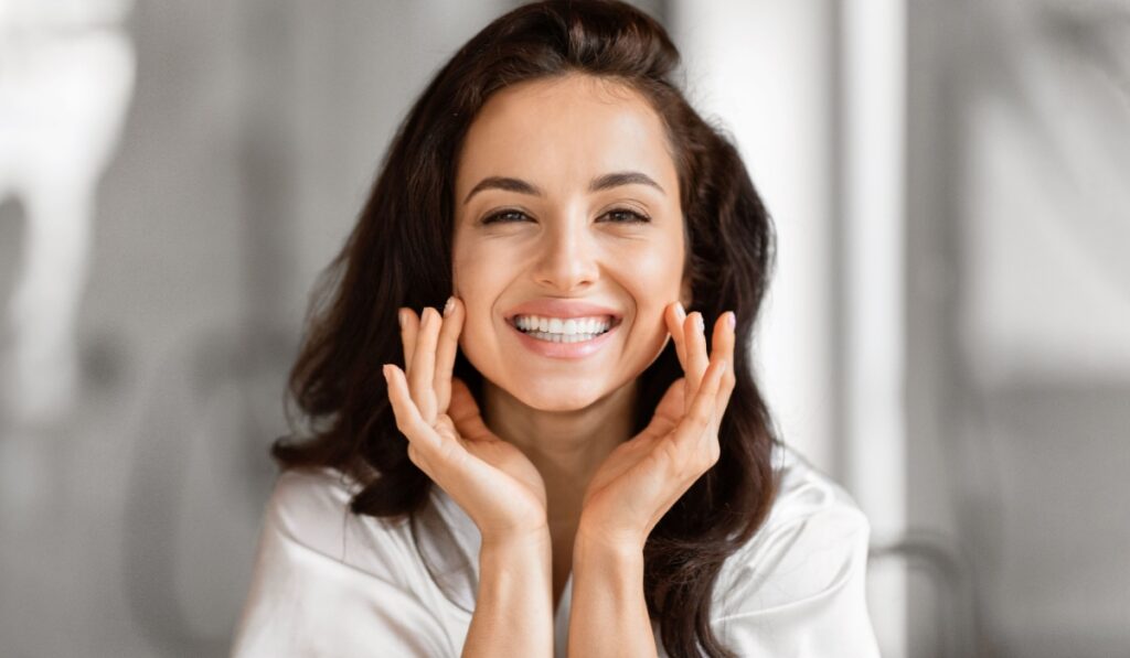 A happy beautiful woman is pampering her skin in the bathroom focusing on skin care routine and beauty