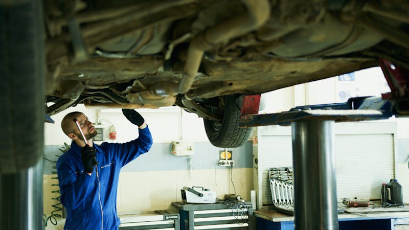 mechanic working on undercarriage of a car