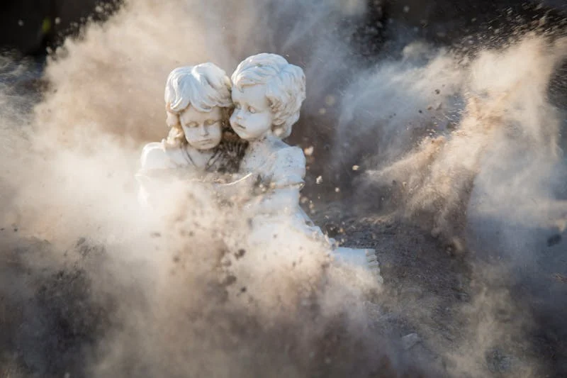 a stone statue of young girls surrounded by dust