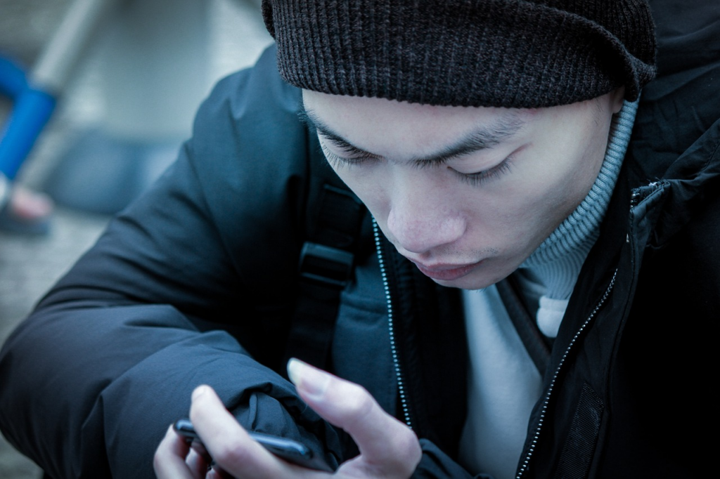 a man scrolling hunched over his phone