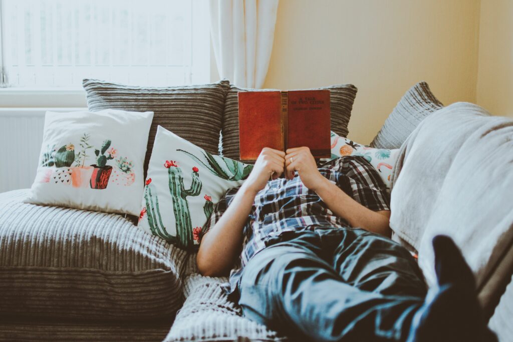 person lying on the couch reading a book 