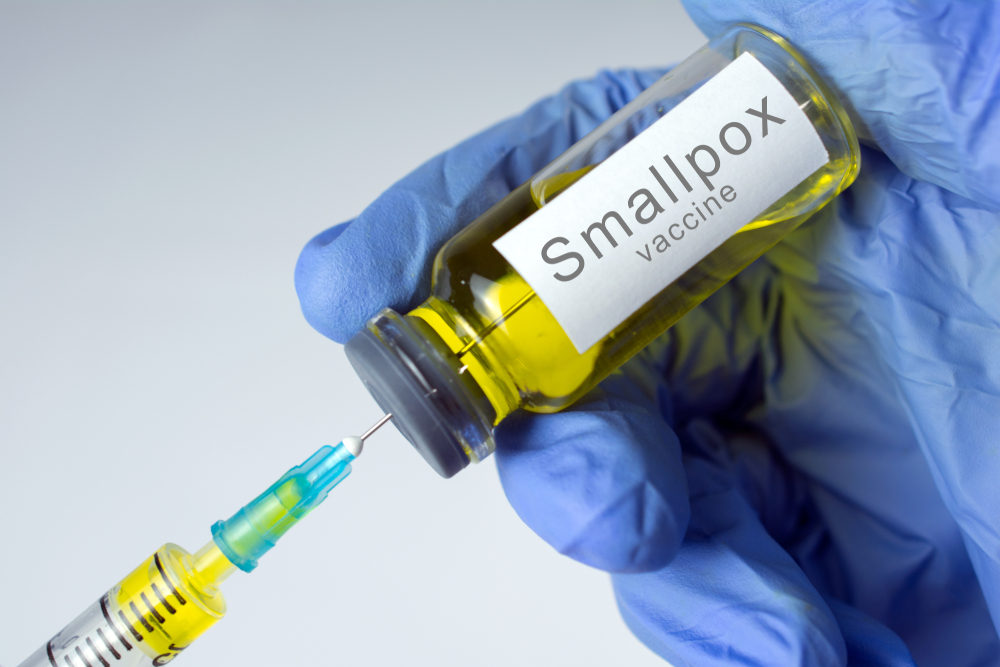 Hands in blue gloves are typing a yellow vaccine in a syringe. Smallpox vaccination concept. close-up, selective focus
