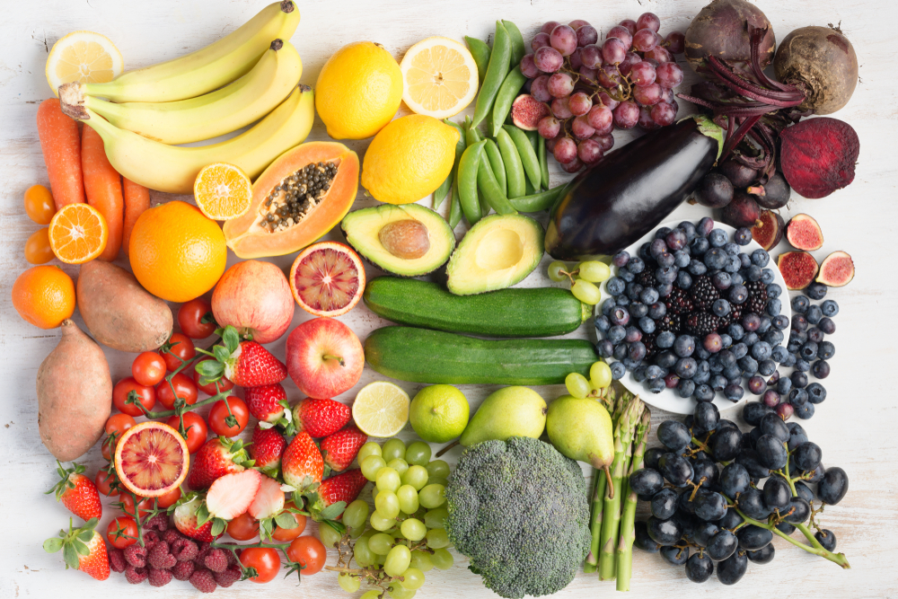 Healthy eating concept, assortment of rainbow fruits and vegetables, berries, bananas, oranges, grapes, broccoli, beetroot on the off white table arranged in a rectangle, top view, selective focus