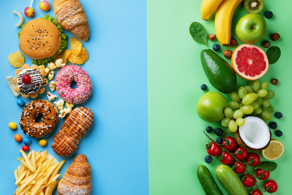 Healthy and unhealthy food background from fruits and vegetables vs fast food, sweets and pastry top view. Diet and detox against calorie and overweight lifestyle concept.
