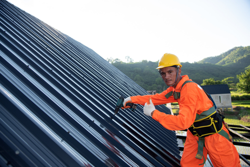 Workers wear protective clothing Roof construction, new roof installation, roofing tools, electric drill used on new roofs with sheet metal construction