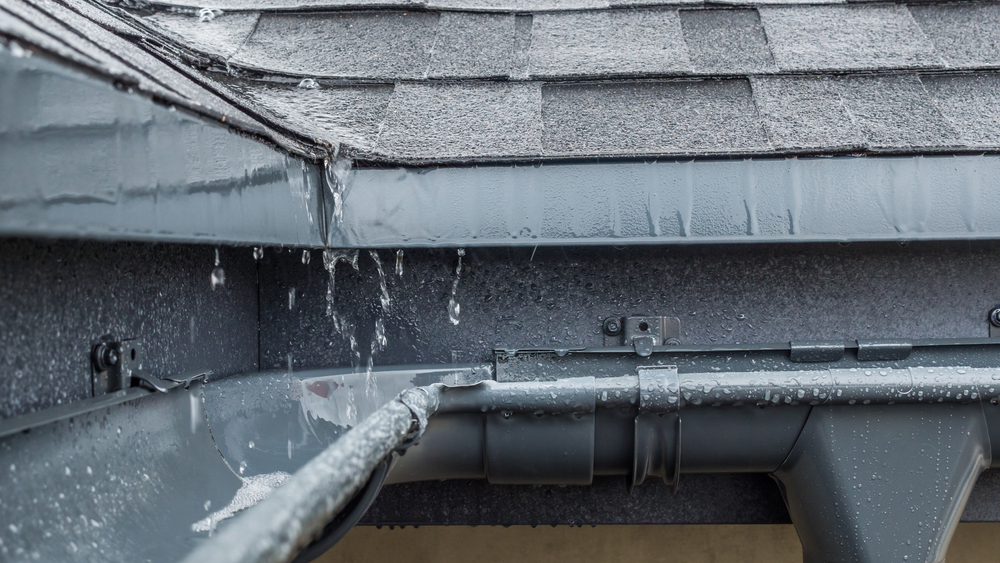 Jets of rain drain into the drainage system on the roof of the house
