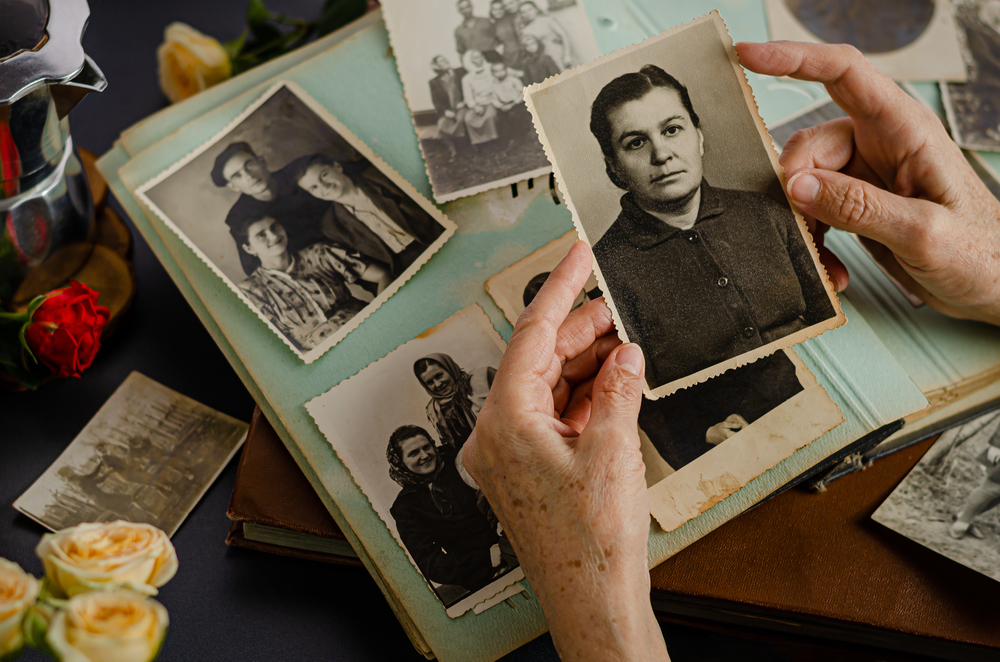 Female hands holding and old photo of her mother. Vintage photo album with photos. Family and life values concept.
