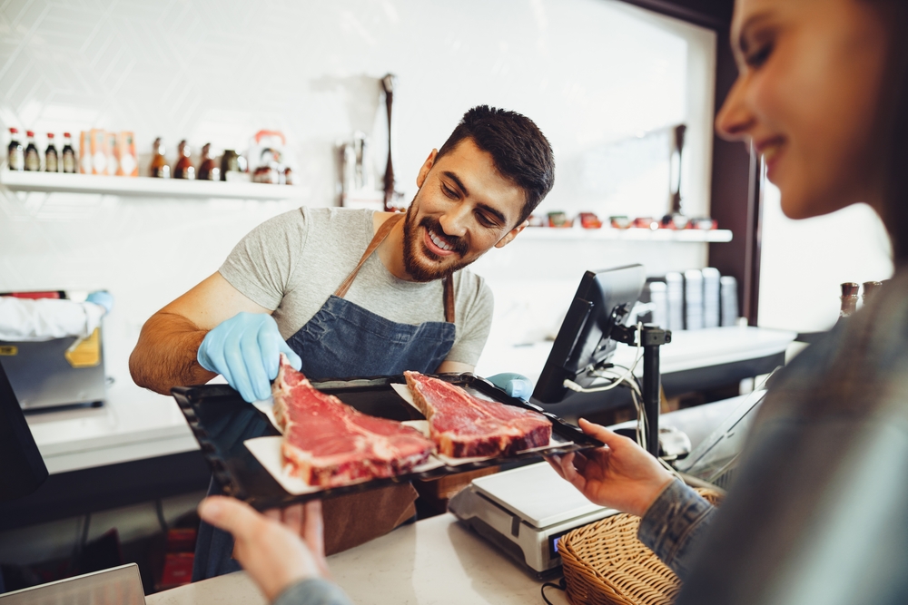 Butcher's shop seller helps to choose product to woman customer