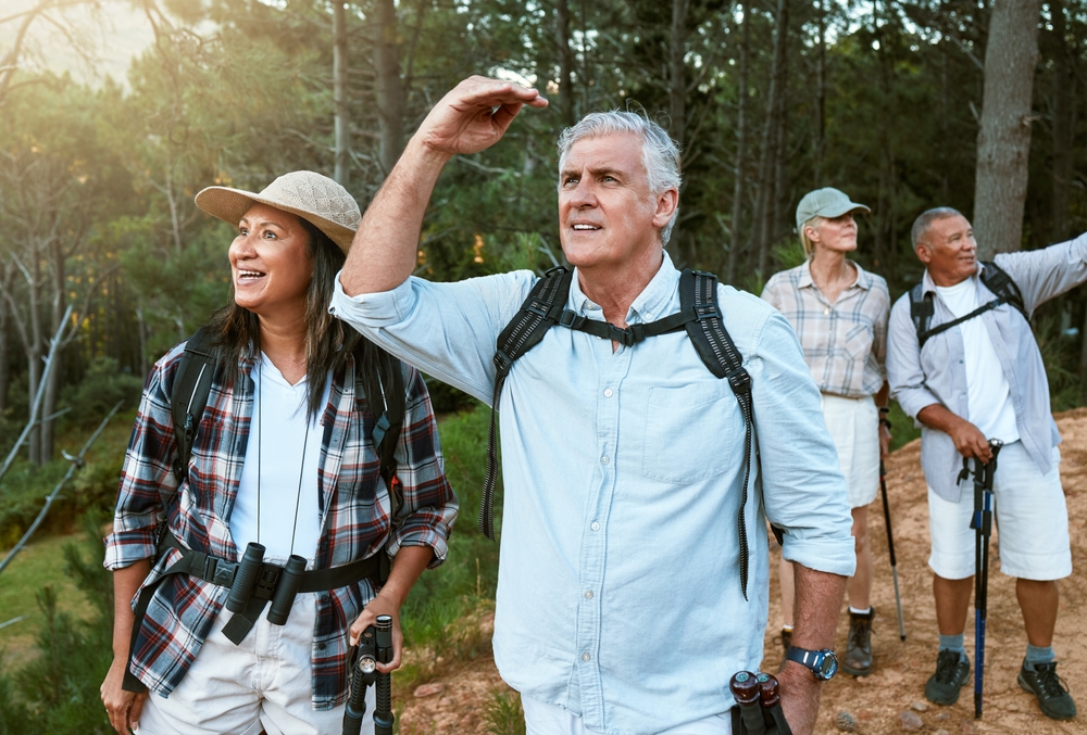 . Hiking, adventure and exploring with a group of senior friends having fun, exercising and enjoying the outdoors. Walking, discovery and journey with old people sightseeing in the forest or woods.