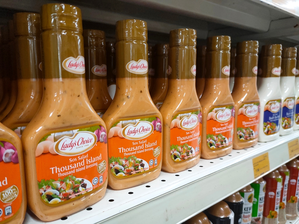 MELAKA, MALAYSIA -JANUARY 4, 2022: Various types of salad dressing in commercial packs are displayed for sale in a supermarket. Separated by brand and flavor. Marked with a price tag.

