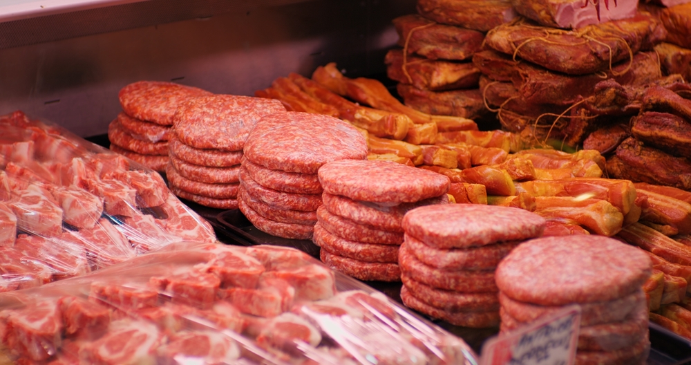 Raw minced meat beef burger cutlets in a window shop. Beef burgers and other meat preps ready to be sold. Food industry.
