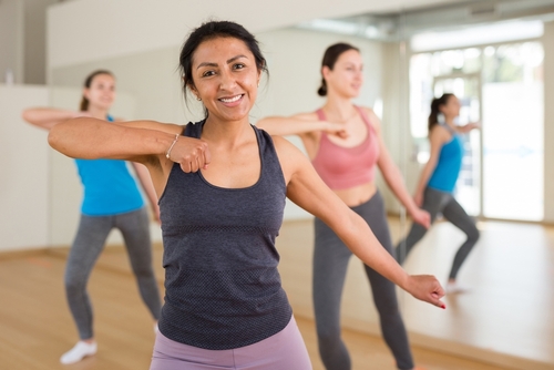 Young adult colombian woman dancing during group class in dance center
