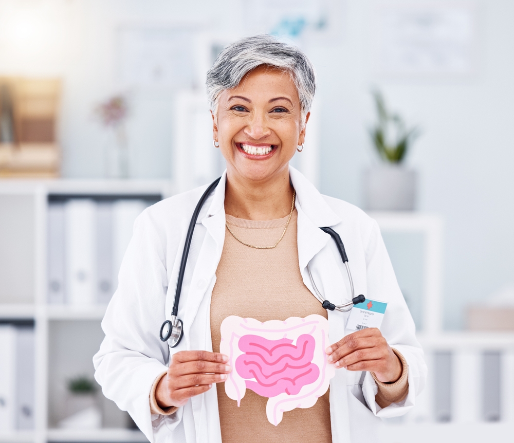 Portrait, doctor and mature woman with intestine model in hospital clinic. Face, gastroenterology and medical professional smile for healthcare of gut, wellness of digestive system and colon anatomy
