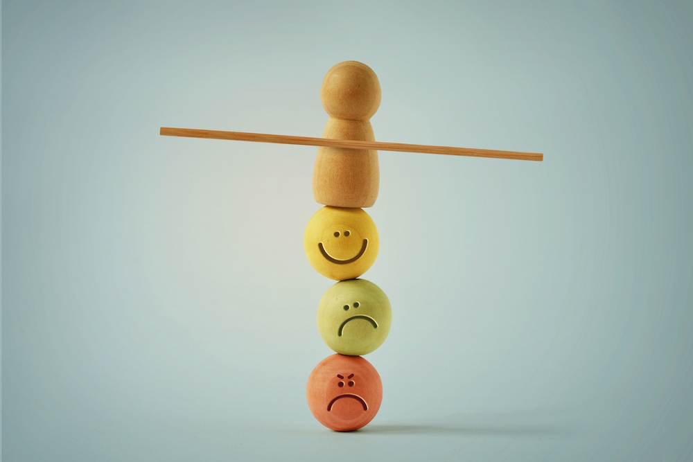 Wooden pawn balancing on beads faces with different mood expressions - Concept of emotional and mental balance