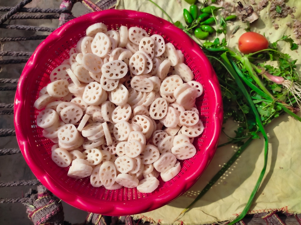 Edible Lotus Root or Lotus stem is known for its crunchy texture and slightly sweet taste. Group of lotus root vegetable sliced placed on red plastic basket. Food concept. Top view. Daylight photo