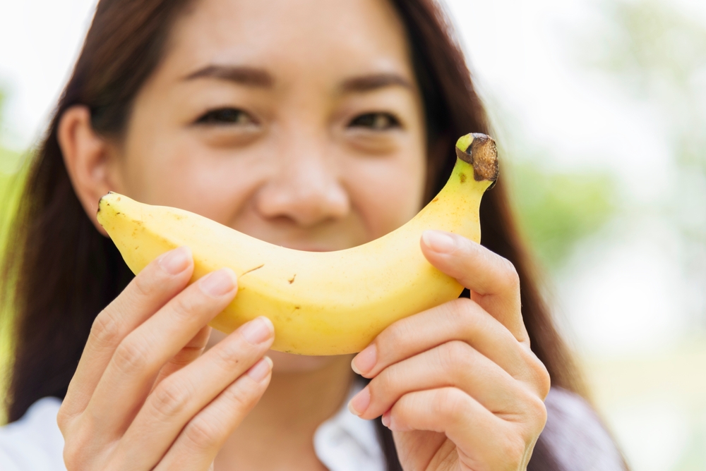 Banana Healthy eating young woman workout holding organic banana fruit healthy lifestyle. Wellness Asian women use yellow banana smile face look at camera. Beautiful healthcare nutrition lifestyle
