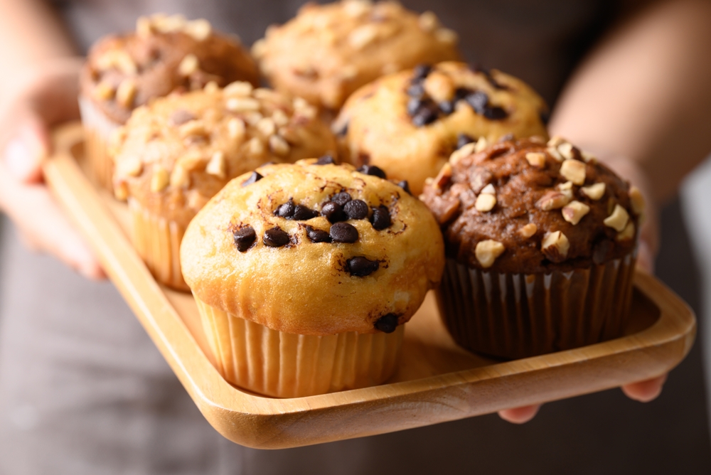 Vanilla chocolate chips muffin, Chocolate almond muffin and Vanilla almond muffin on wooden plate holding by hand
