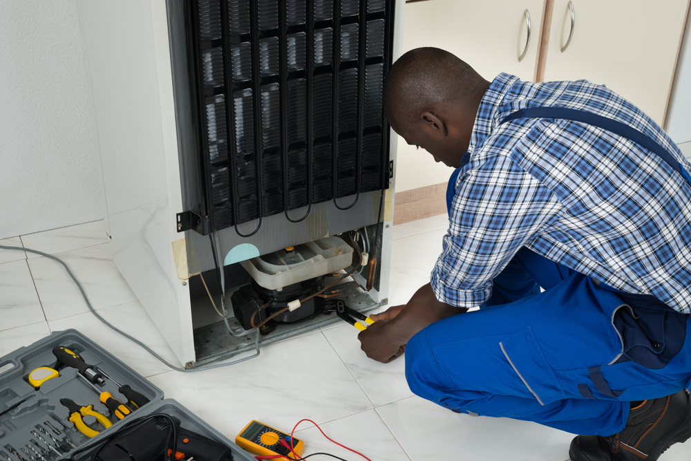 Young African Technician Fixing Refrigerator With Worktool