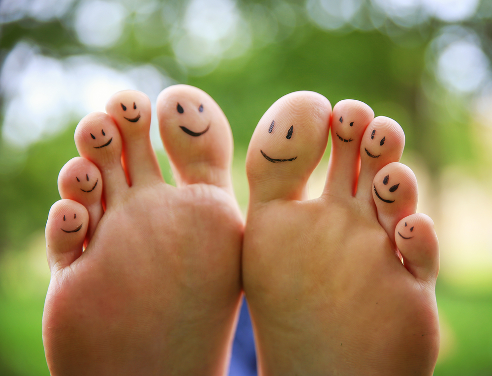 smiley faces on a pair of feet on all ten toes (VERY SHALLOW DOF - big toe on the right) in a park setting