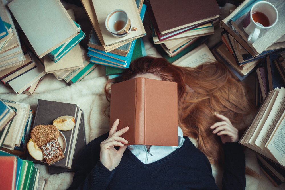 Girl sleeping near books with and cups of tea

