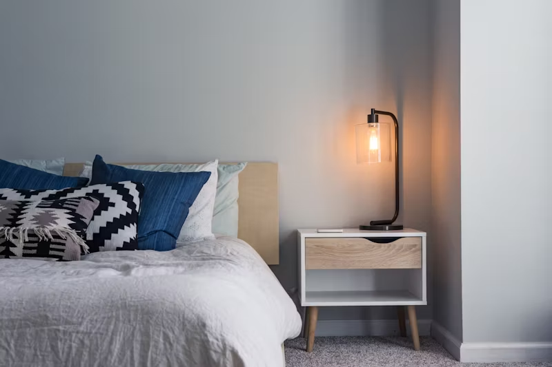 a bedroom with a side table light on