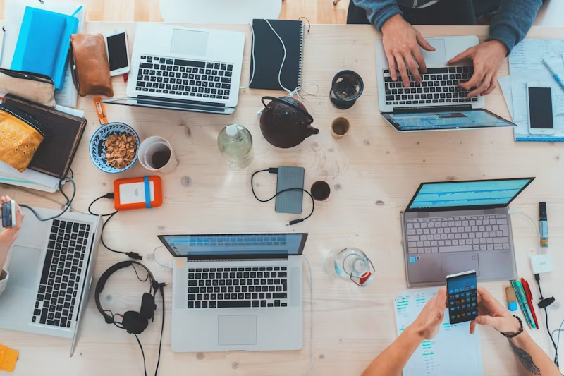 multiple people working with electronics at a table together 