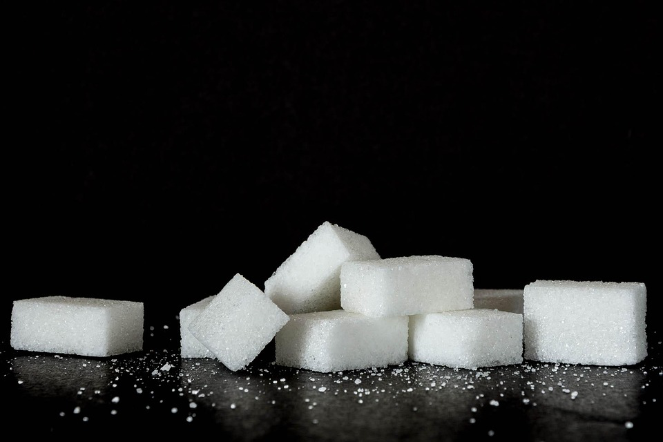 An artistic display of sugar cubes set against a dark black backdrop, emphasizing their white color and geometric shapes.