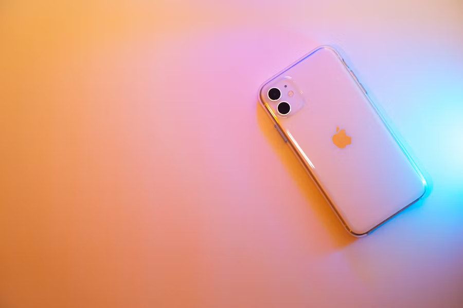 An Apple iPhone illuminated by vibrant, colorful lights.