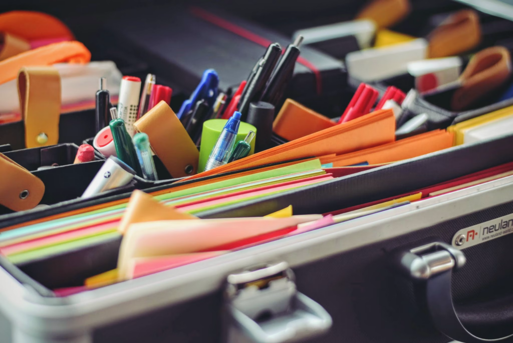 A suitcase overflowing with various office supplies, including pens, notebooks, and folders, ready for organization.