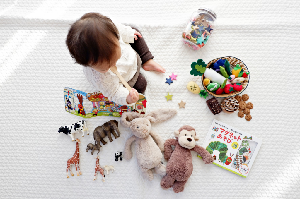A baby joyfully playing with colorful toys on a soft bed, surrounded by a cheerful atmosphere.