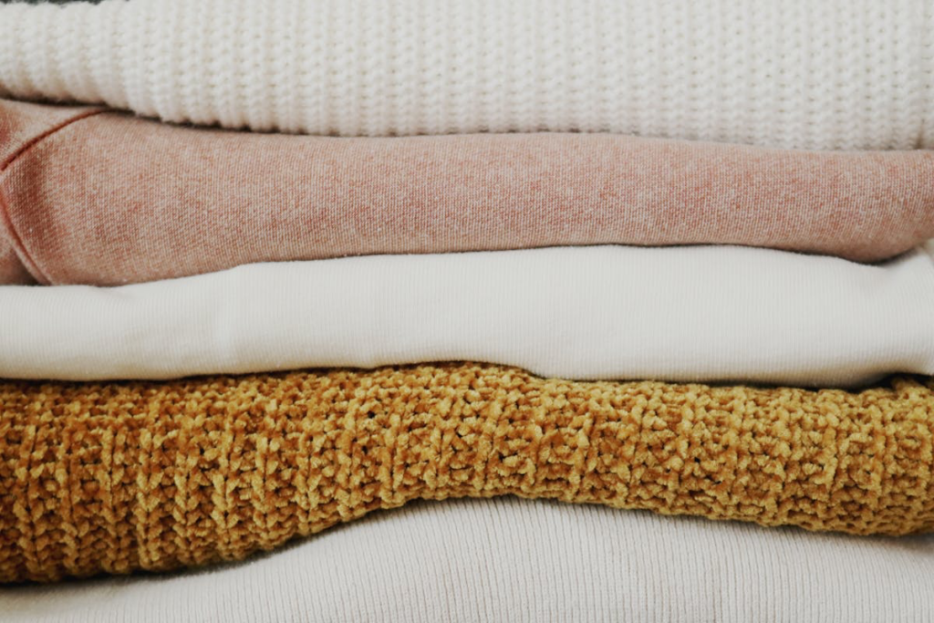 A cozy assortment of blankets, and knitted items stacked together, showcasing various textures and colors.