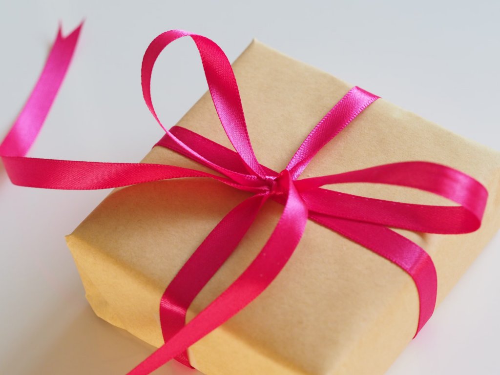 A brown gift box adorned with a pink ribbon, elegantly tied, ready for presentation.