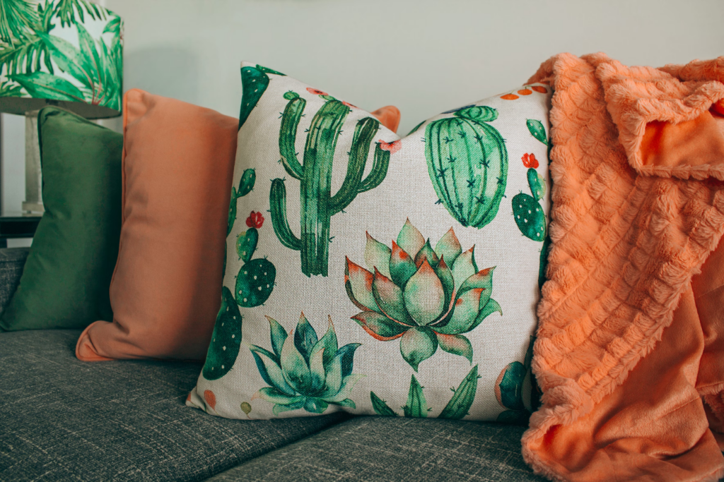 A cozy decluttered couch adorned with a decorative pillow featuring a vibrant cactus print.