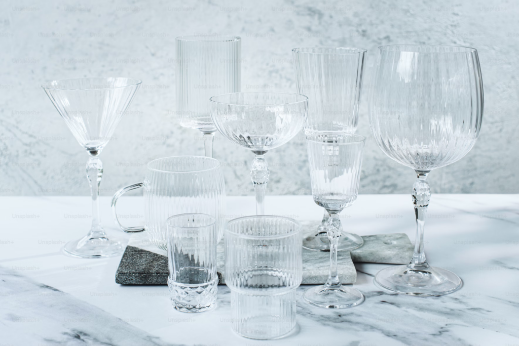A variety of glasses and wine glasses elegantly arranged on a polished marble counter.