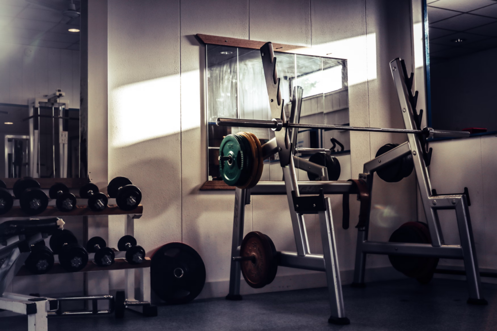 A gym room featuring weights and a large mirror, designed for fitness training and exercise routines.
