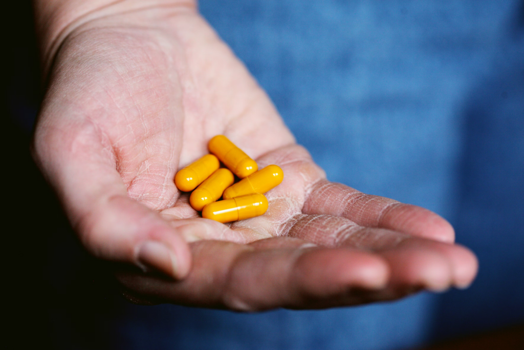 A person holding a handful of various pills, symbolizing medication or health management.