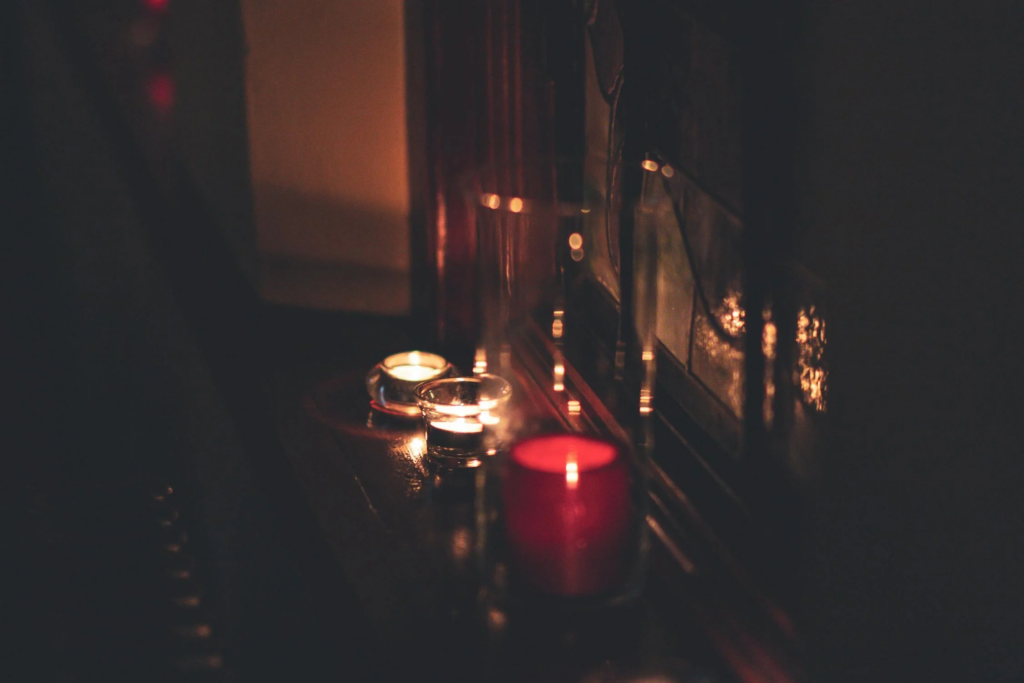Candles arranged on a decluttered window sill, casting a warm glow and creating a serene atmosphere in the room.
