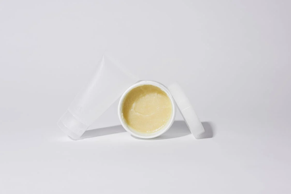 A jar and tube of balm, designed for moisturizing and treating dry skin, including underarm areas.